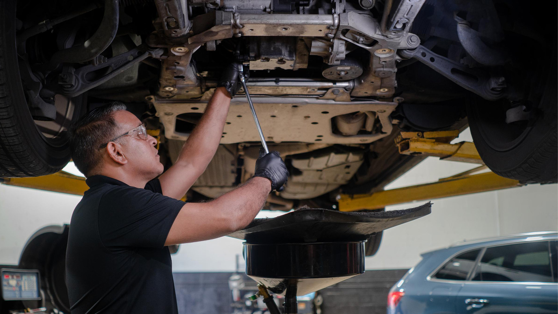 Prestige Auto Tech mechanic under a car on a lift